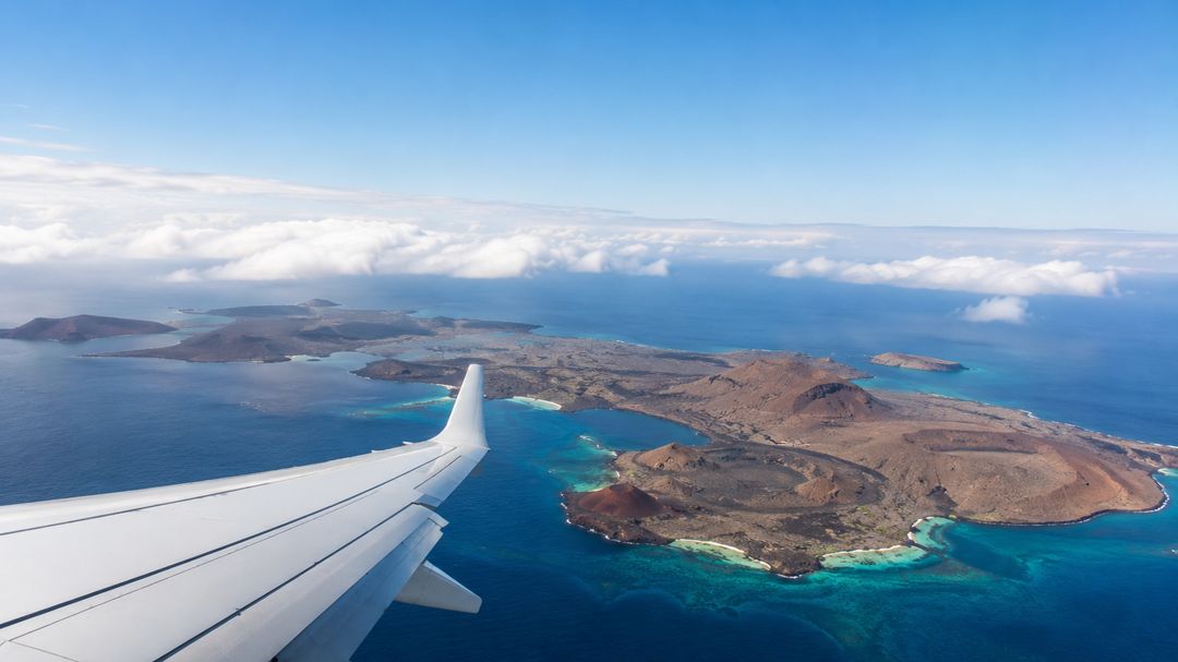 The Galápagos archipelago seen from the window of a descending aircraft, with the wing in frame
