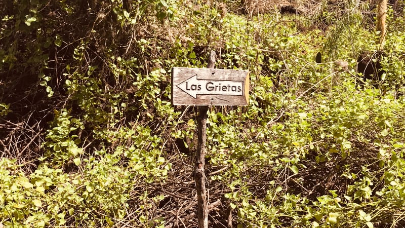 The sign on the trail. The walk in is part of it — On the path to Las Grietas, Santa Cruz, January 2019 — our own photograph